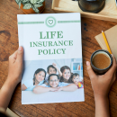 Hands holding a life insurance policy booklet and a cup of coffee